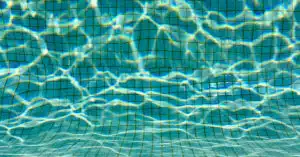 Le fond d'une piscine à carreaux avec les reflets du soleil dans l'eau