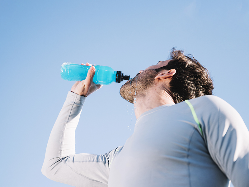 Un homme qui s'hydrate avec une boisson minéralisée pendant son sport en pleine canicule