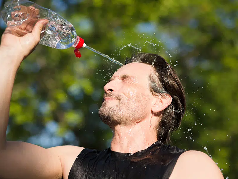 Un homme qui s'asperge le visage d'eau pendant son sport en pleine canicule