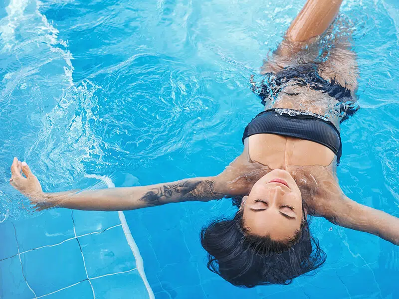 Une femme qui flotte dans une piscine en faisant l'étoile de mer