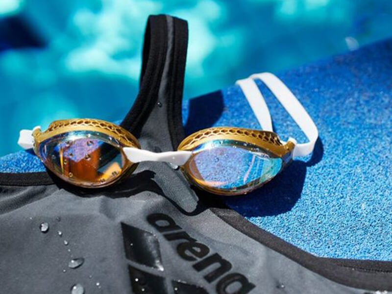 Swimming goggles and a swimming costume by the pool
