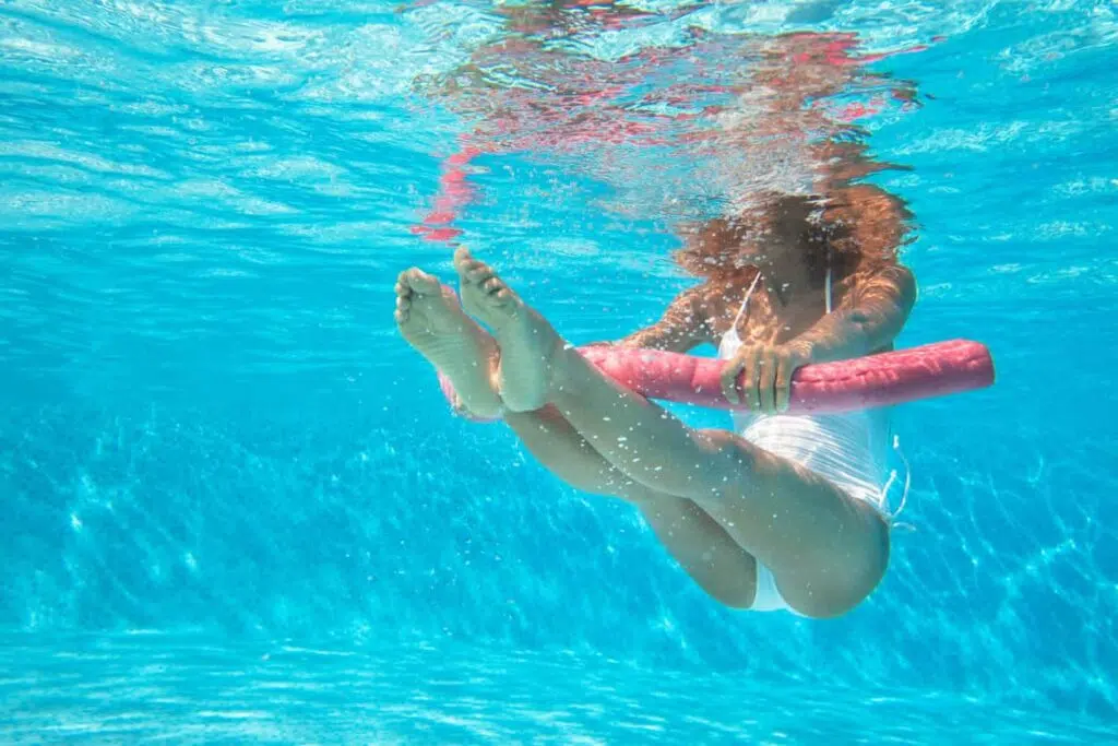 exercice aquagym avec frite : une femme fait un exercice de natation avec une frite